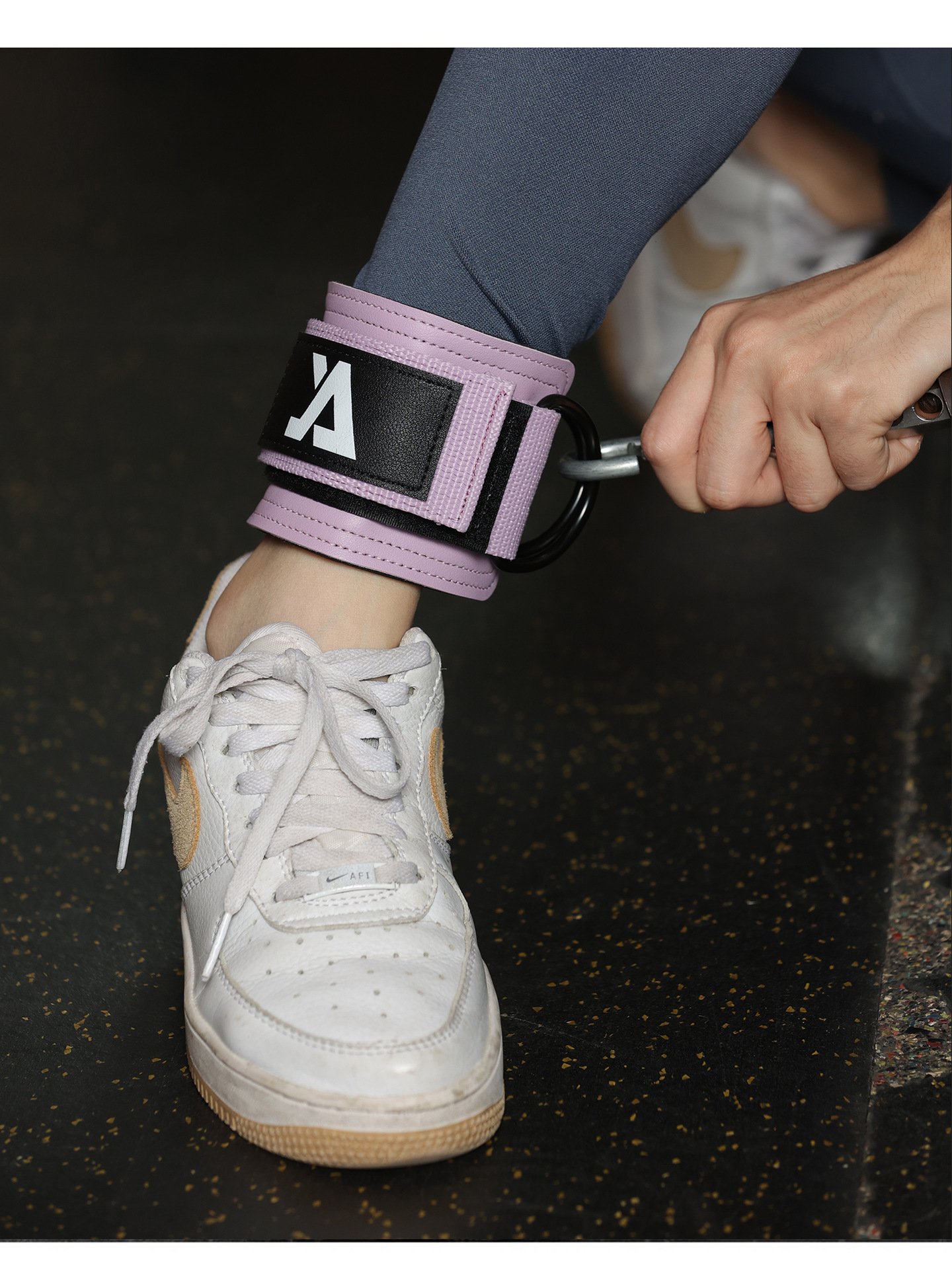 Athlete using ankle sraps for cable machine in gym workout